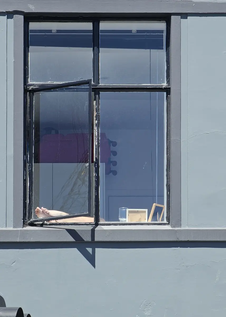 A pair of legs resting on a windowsill in the sun.