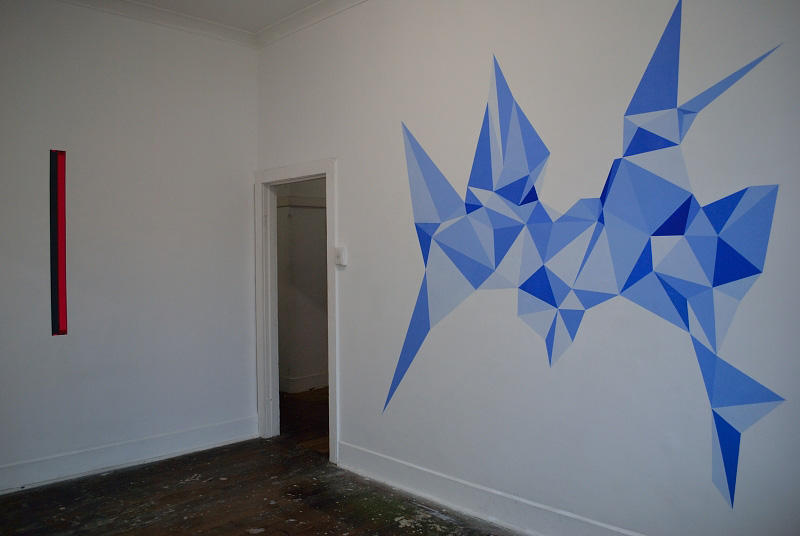 Wall drawing. Cream coloured triangles on white wall.